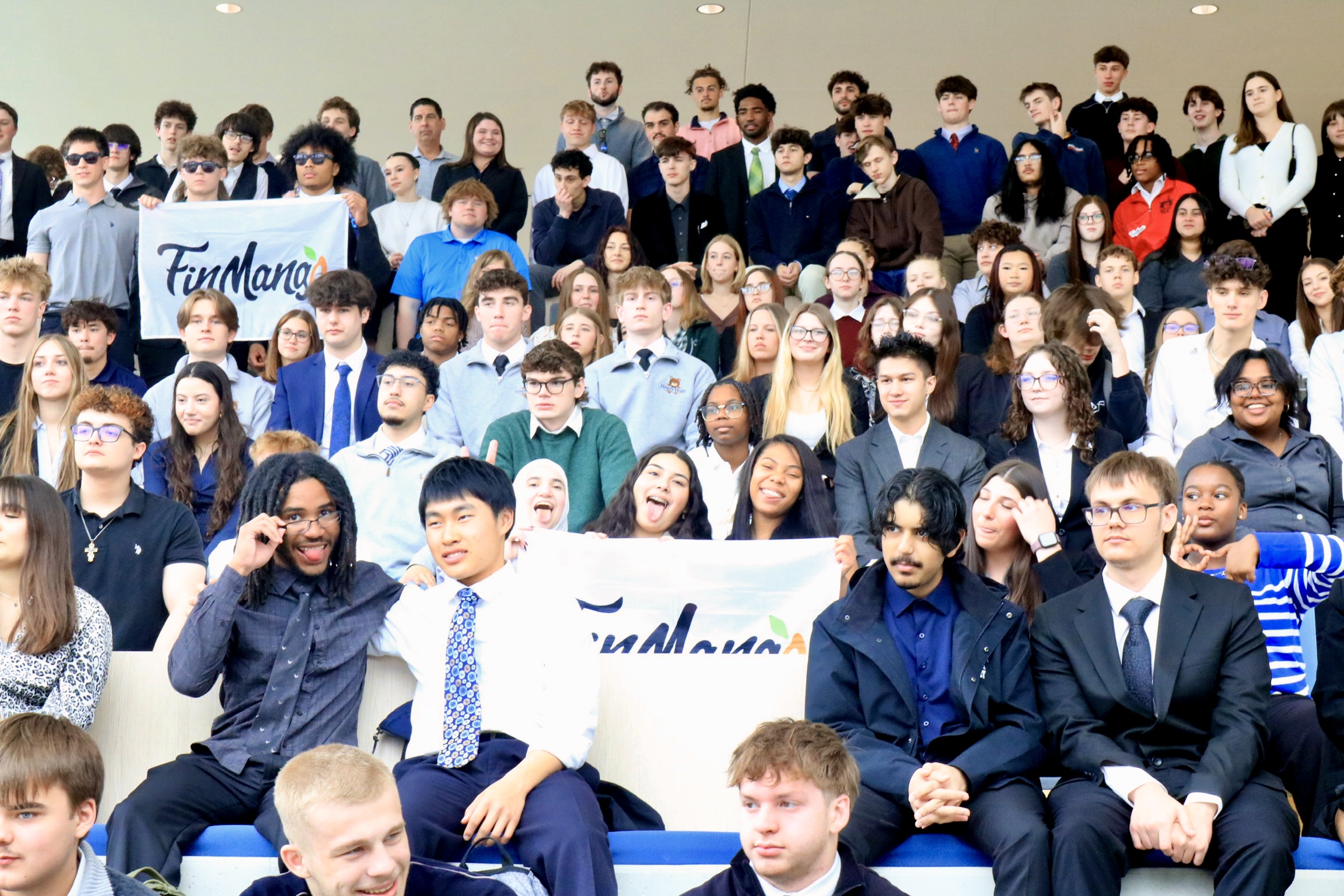 Hundreds of high school students in the Kent State University atrium, two of them holding FinMango flags