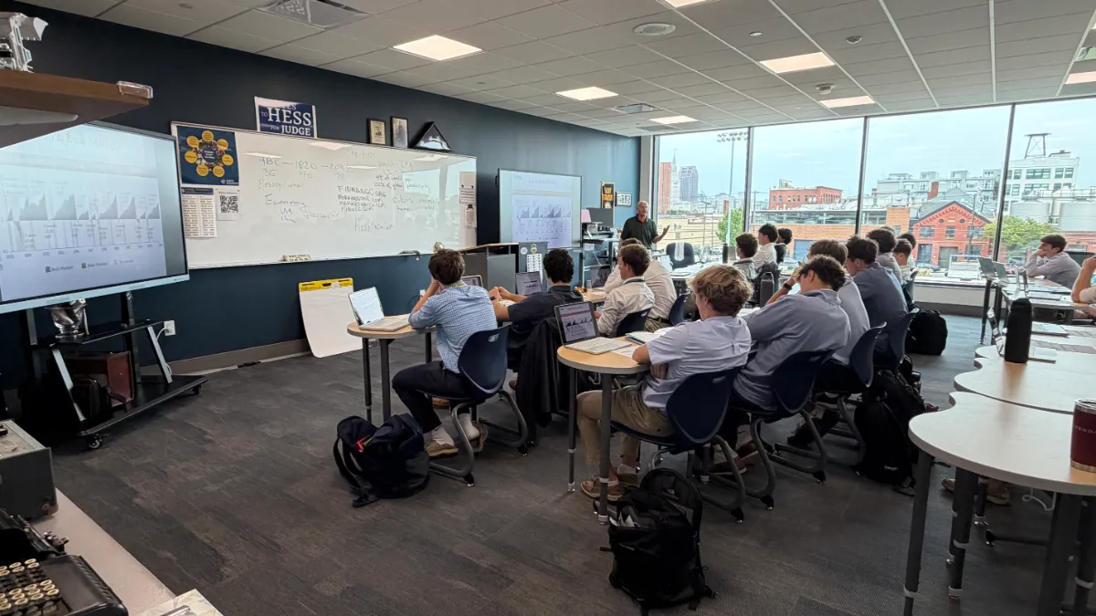 Bob Gillingham teaching a Millionaire Mindset class on bull and bear markets, students at laptops, the Cleveland skyline through the windows
